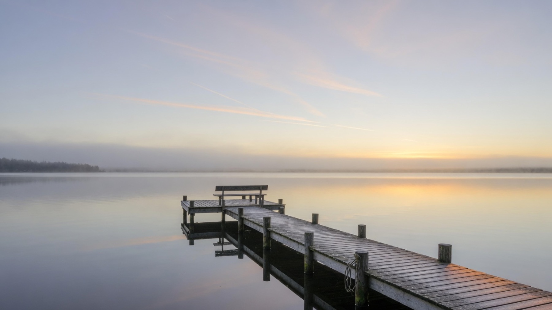 A quiet dock at dawn on still water
